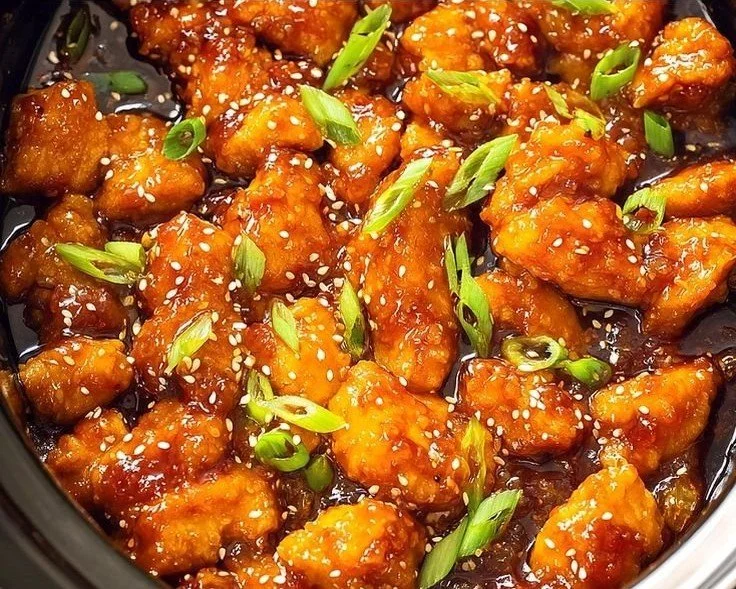 Asian Crockpot Orange Chicken dish served in a bowl with vibrant orange sauce.