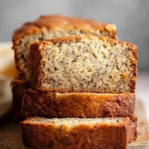 Loaf of homemade banana bread topped with sliced bananas and walnuts