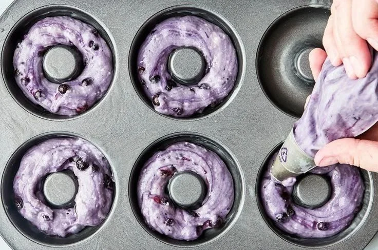 Freshly baked blueberry cake donuts with icing and berries on top