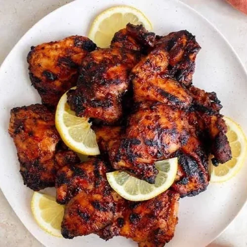 Grilled BBQ chicken thighs sizzling on the barbecue grill