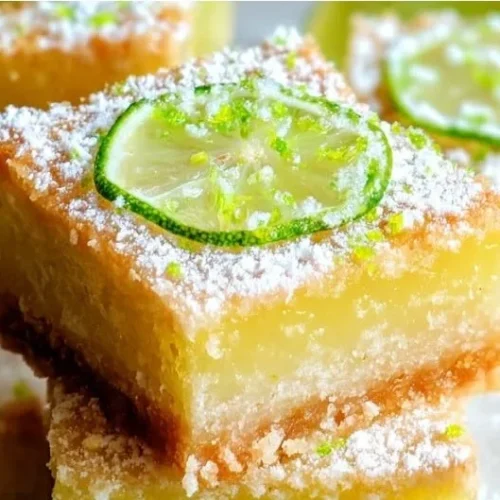 Delicious key lime bars topped with zest and whipped cream for a refreshing dessert.
