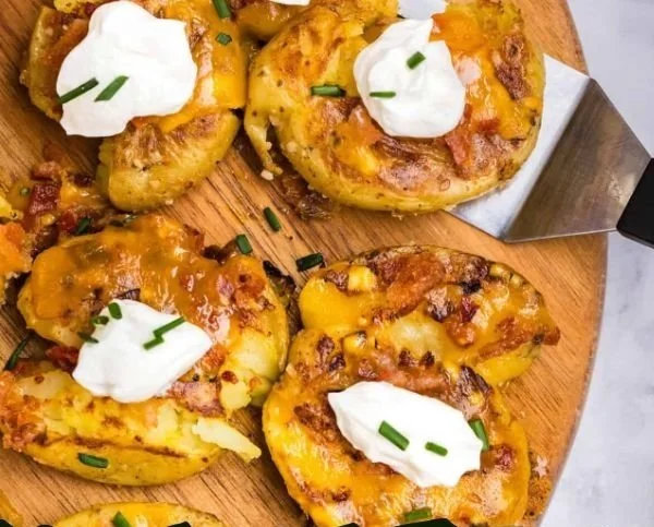 Loaded smashed potatoes topped with cheese, bacon, and chives.