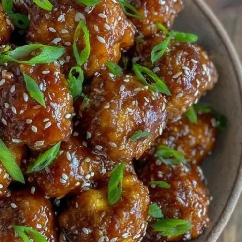 Plate of sticky sesame cauliflower garnished with green onions
