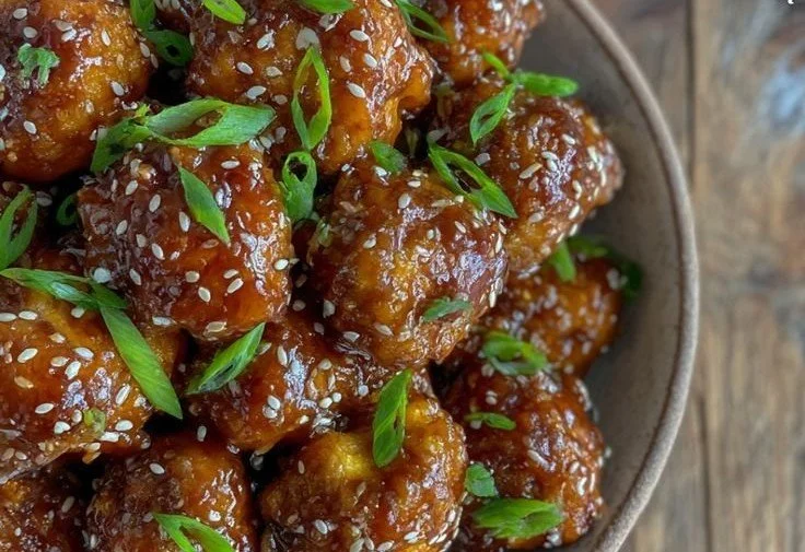 Plate of sticky sesame cauliflower garnished with green onions