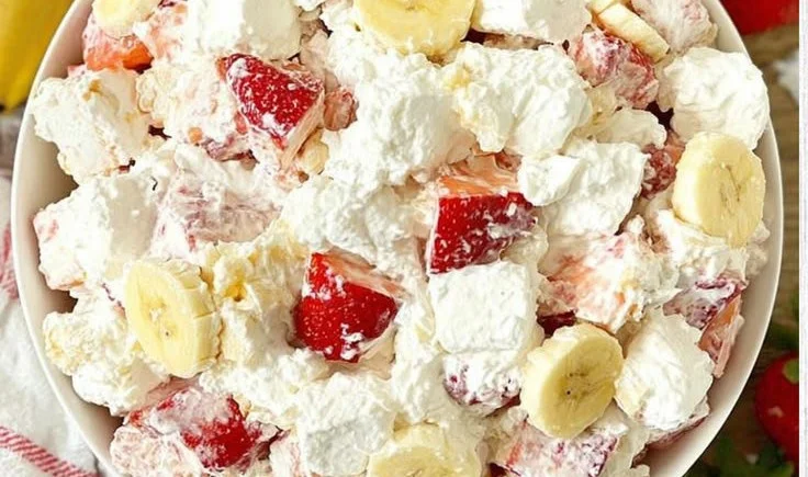 Creamy strawberry banana cheesecake salad served in a bowl with fresh fruit