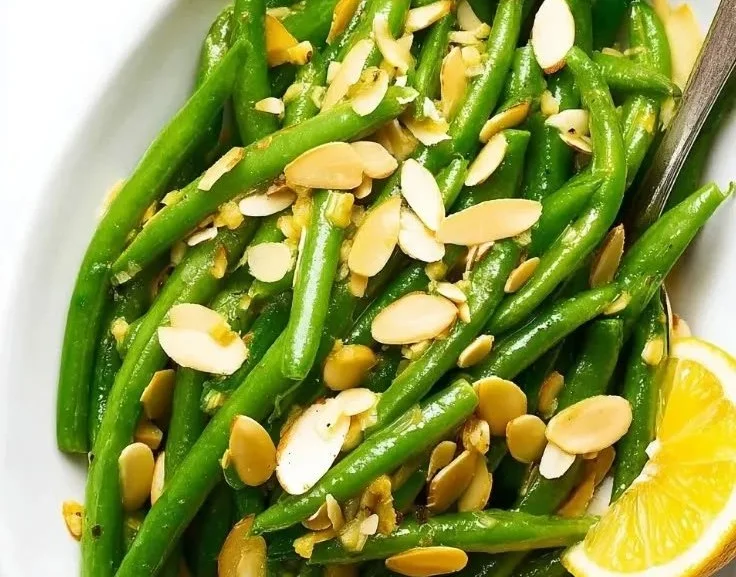 Dish of green beans with roasted almonds on a white plate