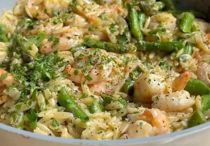 One pan lemon pepper shrimp orzo dish garnished with fresh herbs and lemon slices