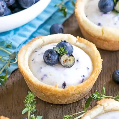 Blueberry cheesecake cookie cups topped with fresh blueberries and whipped cream