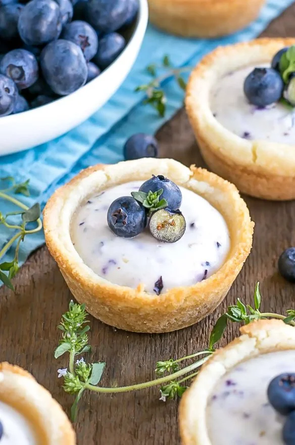 Blueberry cheesecake cookie cups topped with fresh blueberries and whipped cream