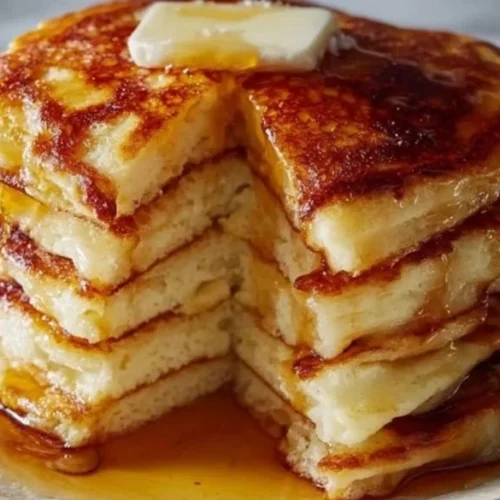 Fluffy buttermilk pancakes stacked with syrup and berries on a plate