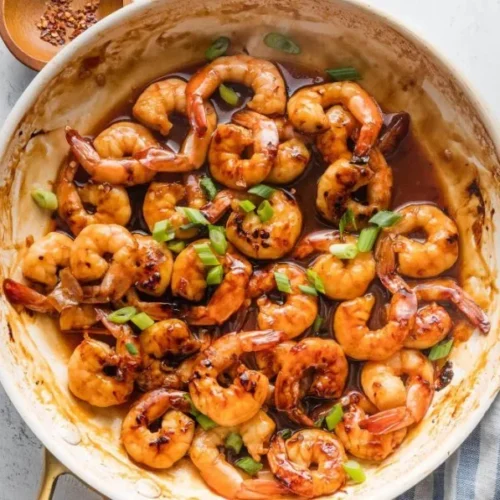 High-protein honey garlic shrimp served with vibrant vegetables on a plate.