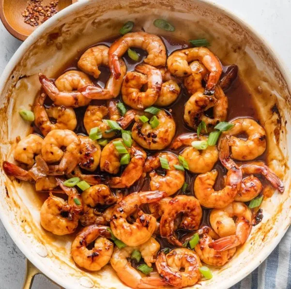 High-protein honey garlic shrimp served with vibrant vegetables on a plate.