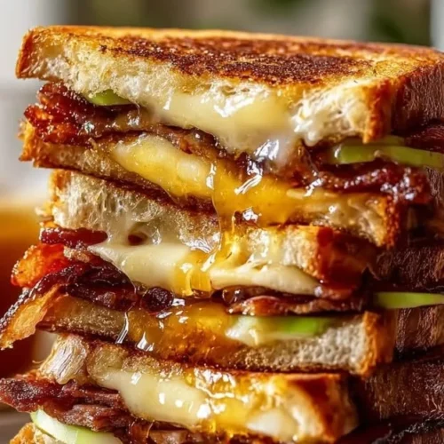 Hot Honey Apple Cheddar Beef Bacon Grilled Cheese sandwich with melted cheese and toppings