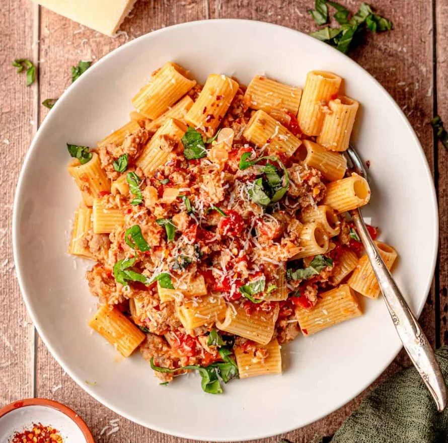 Bowl of creamy Italian sausage pasta garnished with parsley