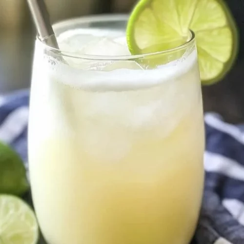 Homemade Brazilian lemonade served in a glass with fresh limes and mint.