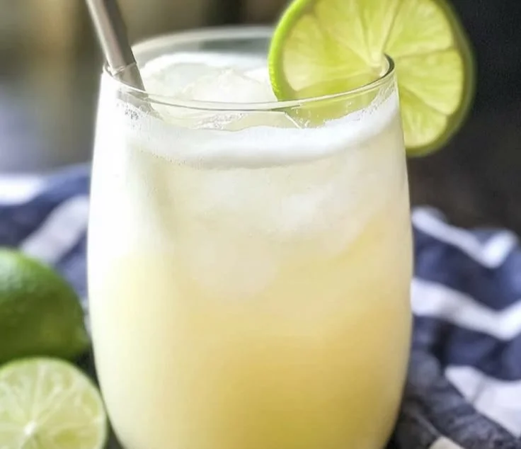 Homemade Brazilian lemonade served in a glass with fresh limes and mint.