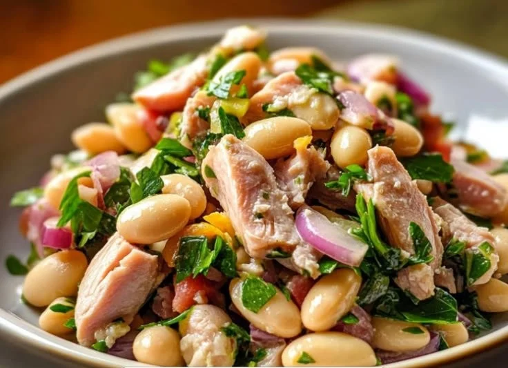 Tuna and white bean salad in a bowl, garnished with herbs and dressing