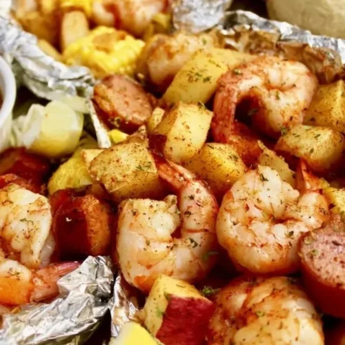 Shrimp boil foil packets with spices and vegetables ready for grilling.