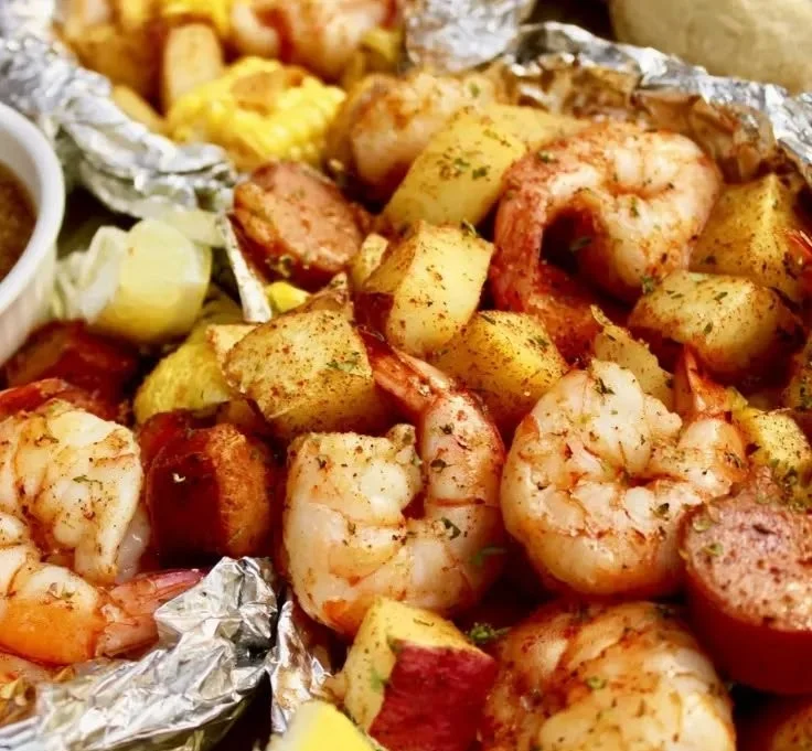 Shrimp boil foil packets with spices and vegetables ready for grilling.