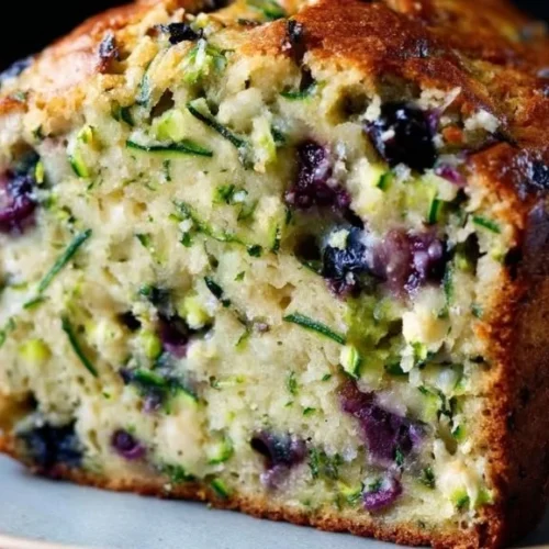 A delicious slice of moist blueberry zucchini bread on a plate.
