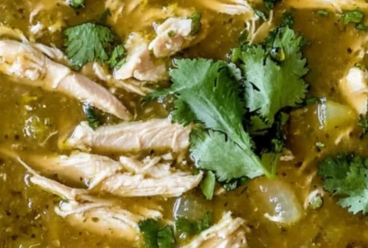 Bowl of roasted tomatillo chicken soup garnished with cilantro and lime.