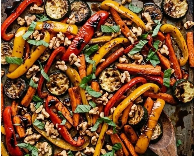 Plate of roasted vegetables topped with walnuts and drizzled with balsamic vinaigrette.