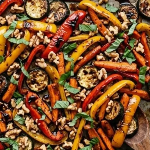 Bowl of roasted vegetables topped with walnuts and drizzled with balsamic vinaigrette