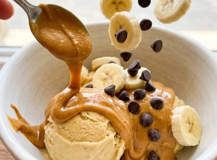 Skinny peanut butter banana frozen yogurt in a bowl topped with sliced bananas