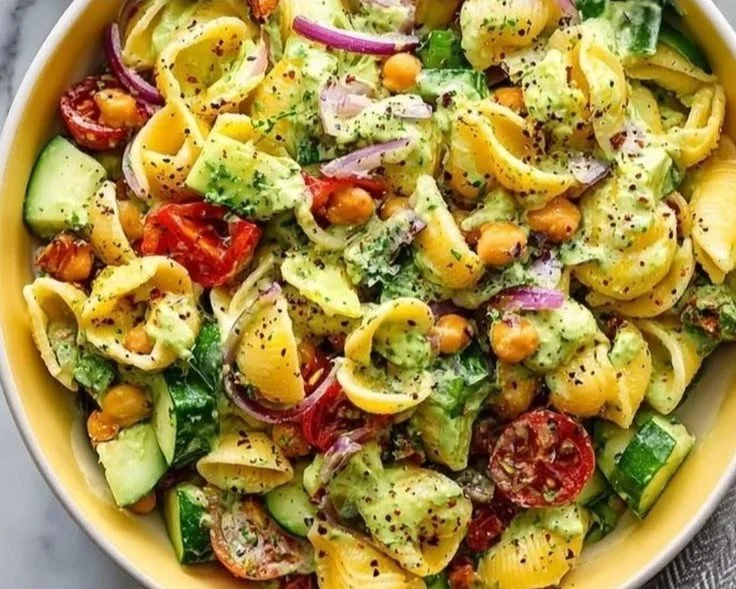 Vegan avocado pasta salad in a colorful bowl, garnished with fresh herbs.