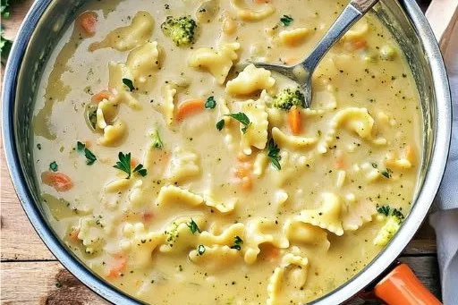 A bowl of creamy pasta soup garnished with herbs and served warm, perfect for comfort food.